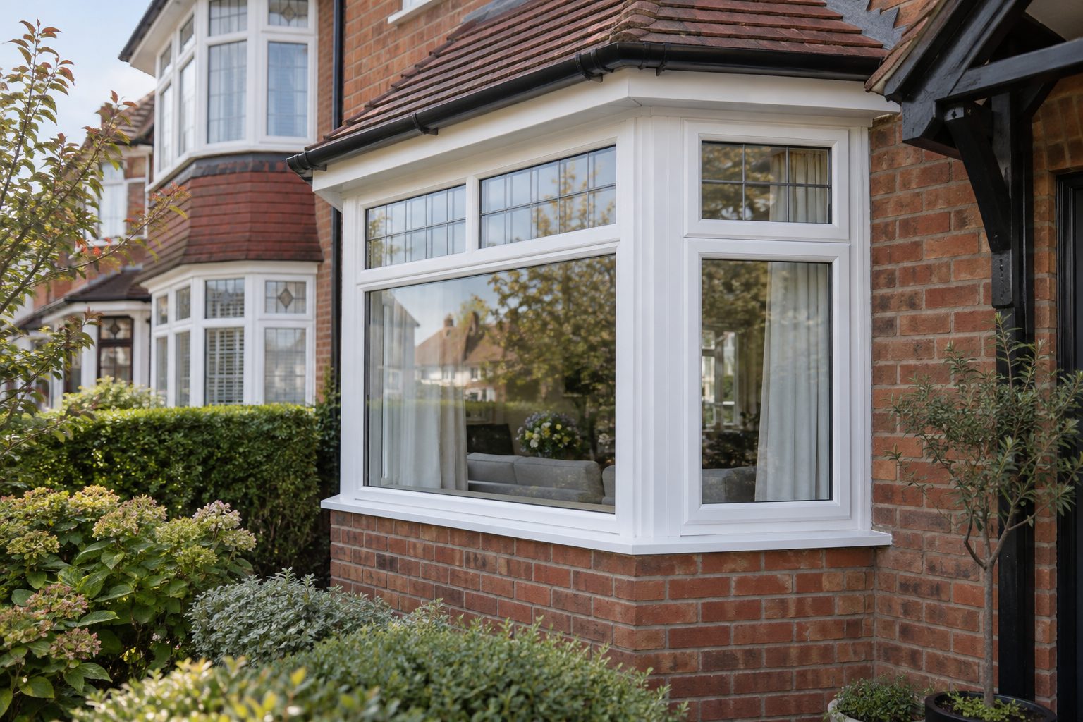 White canted bay window beneath a tiled roof on a brick house